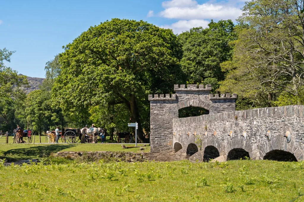 The stone bridge leaving Lord Brandons Cottage with Jarveys, carts and horses on the other side in the distance.